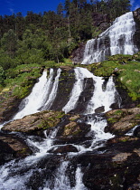 Norway, Rogaland, Svandalsfossen, Waterfall cascading over tiered rock face surrounded by trees near town of Sauda.