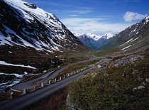 Norway, Sogn og Fjordane, Videdalen, Looking west along winding road with hairpin bend at foot of mountains part covered with snow.