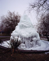 France, Ariege, Town of St Girons, Municipal fountain on traffic island. Water from high pressure hose allowed to create an icy spectacle.