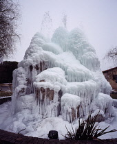 France, Ariege, Town of St Girons, Municipal fountain on traffic island. Water from high pressure hose allowed to create an icy spectacle.