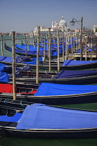 Italy, Venice, Church of Santa Maria della Salute across the Grand Canal as seen from the waterfront of the Piazzetta di San Marco with a row of gondolas in the foreground.