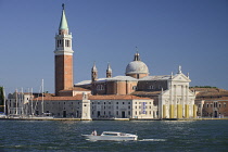 Italy, Venice,Church of San Giorgio Maggiore seen from the waterfront of the Piazzetta San Marco with white speed boat passing.