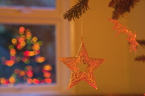 Festivals, Religious, Christmas, Star shaped decoration on tree with lights reflected in window.