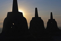 Indonesia, Java, Borobudur, Three stupas silhouetted against the rising sun
