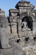 Indonesia, Java, Borobudur, Open-air, seated, granite Buddha next to a similar Buddha in a wall alcove.
