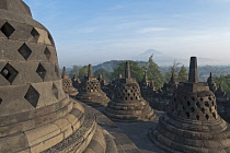 Indonesia, Java, Borobudur, Early-morning, misty view across stupas and the countryside to volcano, Mount Merapi
