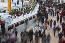 Nepal, Kathmandu, Long exposure showing blur of people walking round the Great Stupa at dusk, with a Western couple standing out, talking to each other.