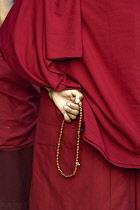 Nepal, Kathmandu, View of the back of a pilgrim Buddhist monk, where one hand is counting off prayers on a string of beads, in front of the Great Stupa.