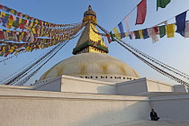 Nepal, Kathmandu, Nepali man sitting alone at the base of the Great Stupa at dusk.