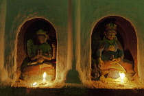 Nepal, Kathmandu, Two small, candle-lit niches in the shrine to Ajima, goddess of smallpox, containing Buddhist deities.