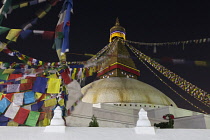 Nepal, Kathmandu, Long-exposure of the Great Stupa illuminated at night, showing blurred Buddhist prayer flags.