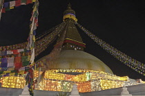 Nepal, Kathmandu, Long-exposure of the Great Stupa illuminated at night in celebration of a full moon, showing blurred Buddhist prayer flags.