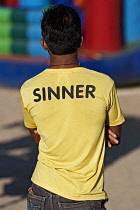 India, Maharashtra, Mumbai, Local male wearing a T-shirt with SINNER printed on it.