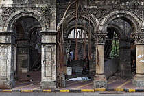 India, Maharashtra, Mumbai, Man asleep on the pavement of a dilapidated, Victorian arcade in Colaba, central Bombay.