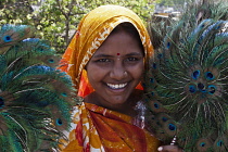 India, Maharashtra, Mumbai, Smiling Hindu woman, in orange sari, selling peacock-feather fans in central Bombay.