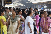 India, Maharashtra, Mumbai, Women waiting on crowded platform of a suburban train station during rush hour.