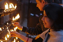 Nepal, Kathmandu, Local woman lighting candles at a street shrine.