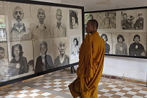 Cambodia, Phnom Penh, Buddhist monk looking a victims' photos, Toul Sleng Genocide Museum S-21. Toul Sleng was a high school, taken over by the Khmer Rouge and turned into a prison, where people were...