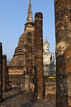 Thailand, Sukothai, Seated, white Buddha in front of large, brick stupa, with row of pillars to one side, Wat Sra Sri.