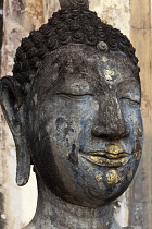 Thailand, Sukothai, Close-up of time-blackened Buddha's face, with the remains of blue and gold paint, Wat Saphan Hin.