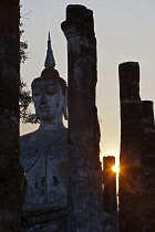 Thailand, Sukothai, Sunset behind a seated Buddha, Wat Mahathat Royal Temple.