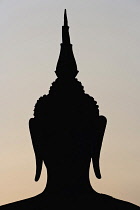 Thailand, Sukothai, Head of a seated Buddha silhouetted at sunset, Wat Mahathat Royal Temple.