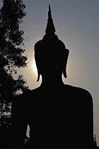 Thailand, Sukothai, Head of a seated Buddha silhouetted at sunset, Wat Mahathat Royal Temple.