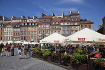Poland, Warsaw, Old Town Square, rynek Starego Miasta, Tourists sat at outdoor restaurant seating area.