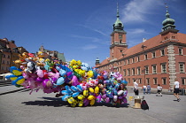 Poland, Warsaw, Old Town, Plac Zamkowy, Arkady Kubickiego, Red Brick Royal Castle with balloon vendor in the foreground.