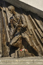 Poland, Warsaw, Monument to the Warsaw Uprising, another section of the monument showing a Polish insurgent actively engaged in combat with bouquet of flowers beneath.