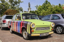 Poland, Warsaw, Ul Krakowskie Przedmiescie or The Royal Way, a colourful Trabant with a statue of the author and poet Adam Mickiewicz in the background.