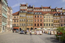 Poland, Warsaw, Stare Miasto or Old Town Square, Colourful facades of buildings on the north side of the square with open air restaurant and artwork on display.