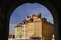 Poland, Warsaw, Colourful facades in Plac Zamkowy or Castle Square viewed through arch of Royal Castle entrance.