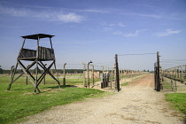 Poland, Auschwitz-Birkenau State Museum, Birkenau Concentration Camp, Guard tower with ruins of former accommodation blocks surrounded by barbed wire fencing.