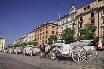 Poland, Krakow, Rynek Glowny or Main Market Square, horse drawn tourist carriages awaiting customers.