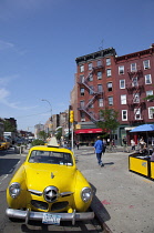 USA, New York State, New York City, Manhattan, Greenwich village, Yellow Studebaker car parked outside the Caliente Cab Co Bar on the corner of Bleecker Street and 7th Avenue.