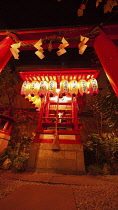 Japan, Kyoto, Nishiki Market on Nisiki koji-dori street, Nishiki Temmangu shrine, an Inari fox shrine with red torii gate, at night, lanterns from donors.