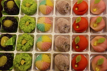 Japan, Kyoto, Nishiki Market on Nisiki koji-dori street, tray of handmade "wagashi" sweets based on sweet beans. made in shapes including persimmon, dried persimmon, and peach, left side with chestnut...
