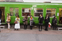 Japan, Tokyo, Shibuya, Group of young women, variety of fashion styes, in line in fron of courtesy car a decommisioned train coach car,  in front of Shibuya station.