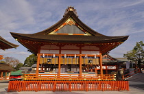 Japan, Kyoto, Vermillion buildings at Fushimi Inari Taisha shrine, offerings of bottles of sake , beer, soy sauce lined up in right building.