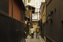 Japan, Kyoto, Traditional style buildings in Gion area, couple walks down narrow alley.