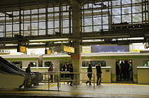 Japan, Tokyo, Tamachi, Yamanote line platform of  Tokyo train station, passengers on train, platform barrier gate.