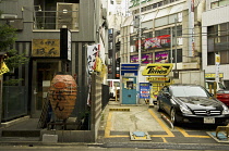 Japan, Tokyo, Gotanda  JR train station,  building with restaurants including Vietnamese, signs and lanterns , large chochin lantern like pig, parking lot with black Mercedes-Benz.