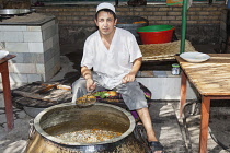 Uzbekistan, Navoi Province, Man cooking plov, typical traditional Uzbek food.