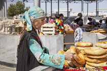 Uzbekistan, Samarkand, Woman buying non bread, Siyob Market, also known as Siab Market.