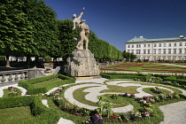 Austria, Salzburg, Mirabell Palace and Gardens with statue and flowerbeds in the foreground.