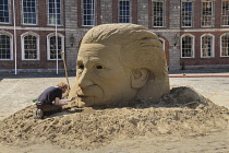 Ireland, Dublin, Dublin Castle, sand sculptor working on a sand sculpture of a face in the courtyard.