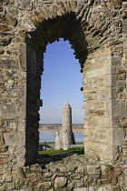 Ireland, County Offaly, Clonmacnoise, Temple Finghin and  McCarthy's Tower viewed through an open window of the cathedral.