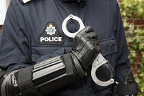 Detail of Police officer wearing body armour and holding Hand Cuffs.