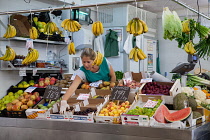 Spain, Andalucia, Cadiz, Grocer arranges her display of fruit at her stall in the Central Market.